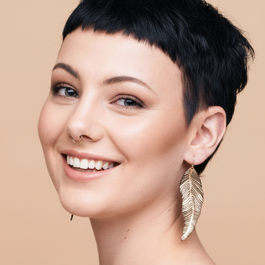 Smiling model with gold feather earrings